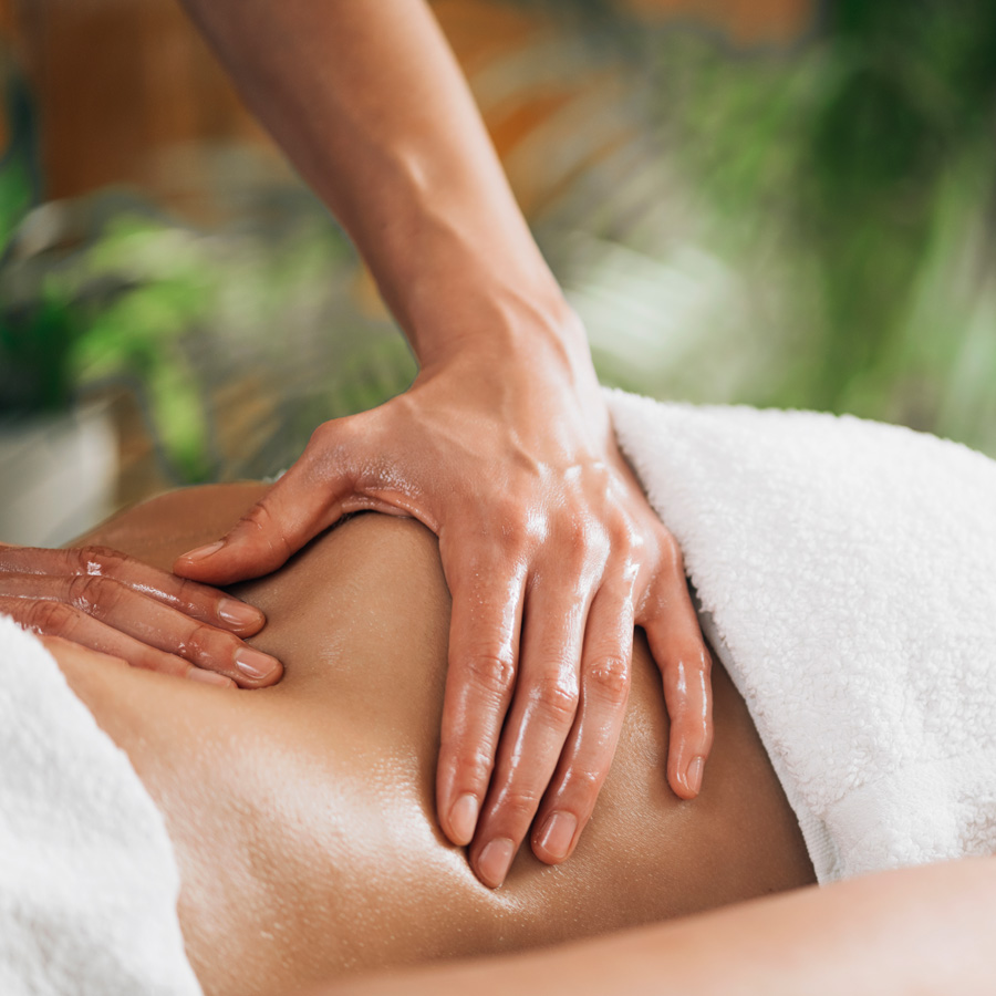 A woman receiving a relaxing back massage in a serene spa environment.